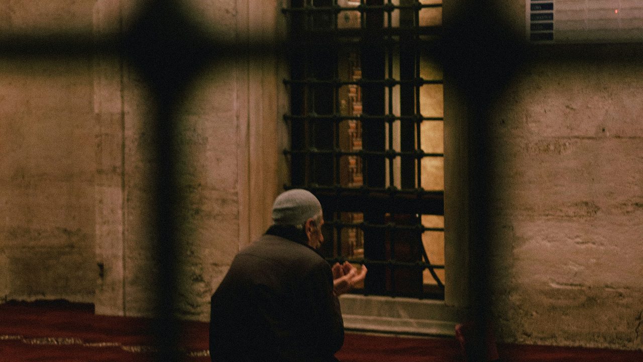 A worshipper sitting quietly in a mosque beside a window