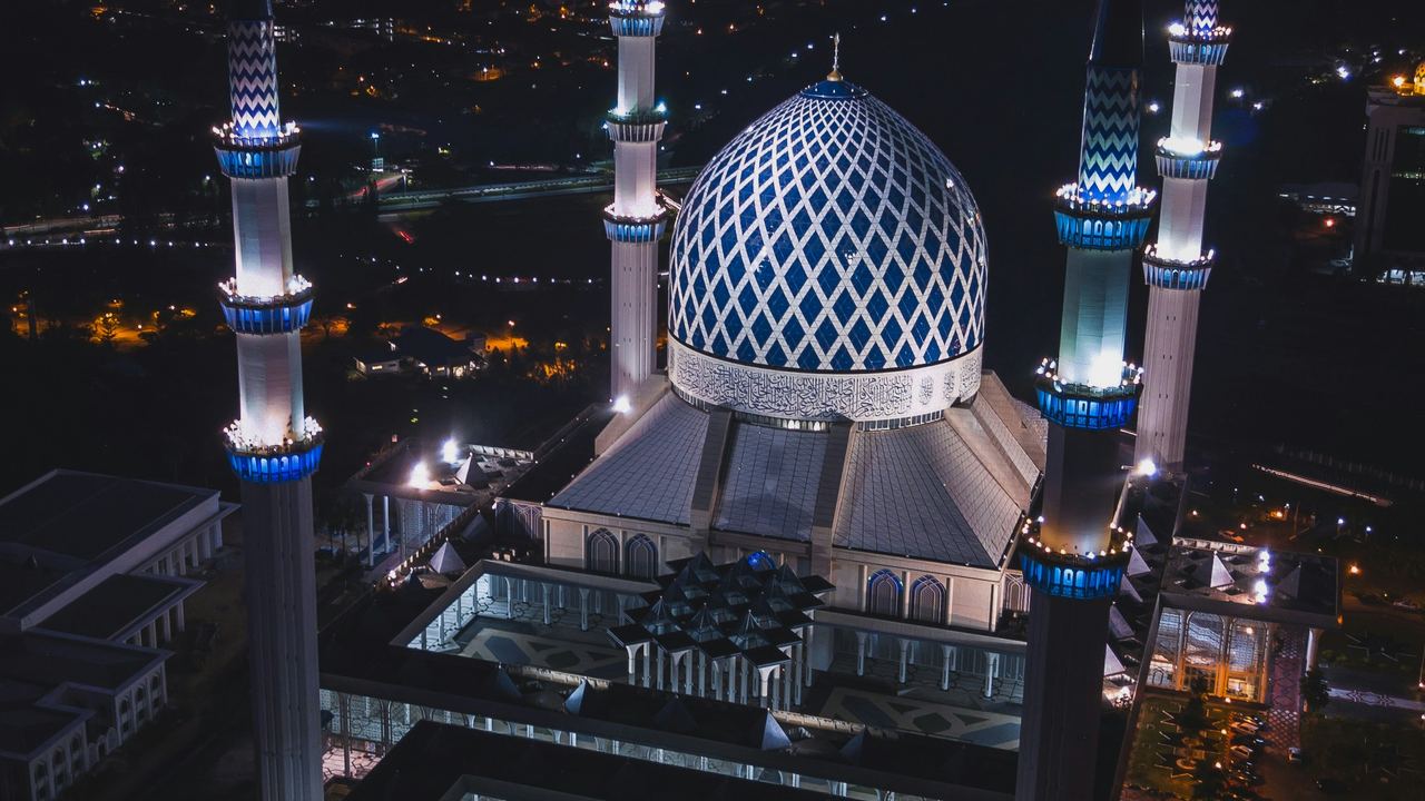 A mosque illuminated against the dusk sky