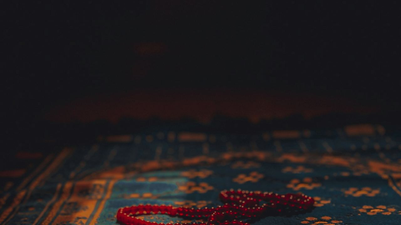 Red tasbih prayer beads resting on a prayer mat